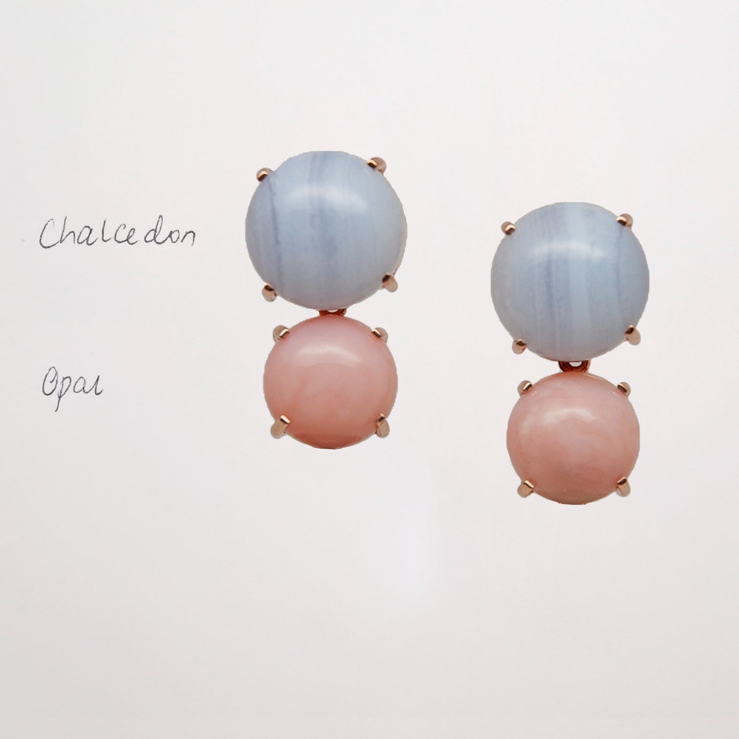 Pair of earrings with pink and blue gemstone on a light gray background