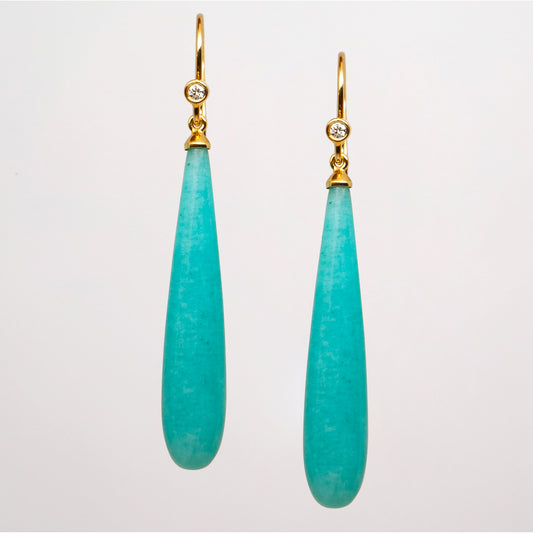 Pair of turquoise teardrop earrings with gold hooks and diamonds on a light gray background