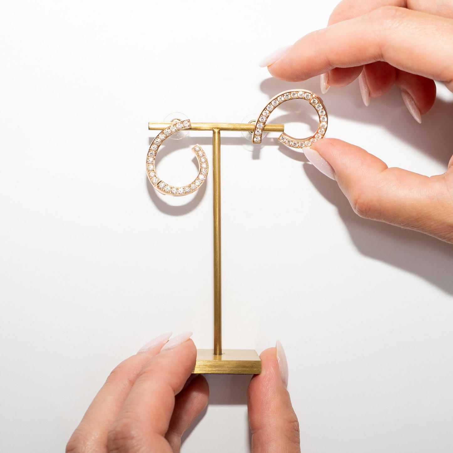 Gold jewelry stand held by hands on a white background