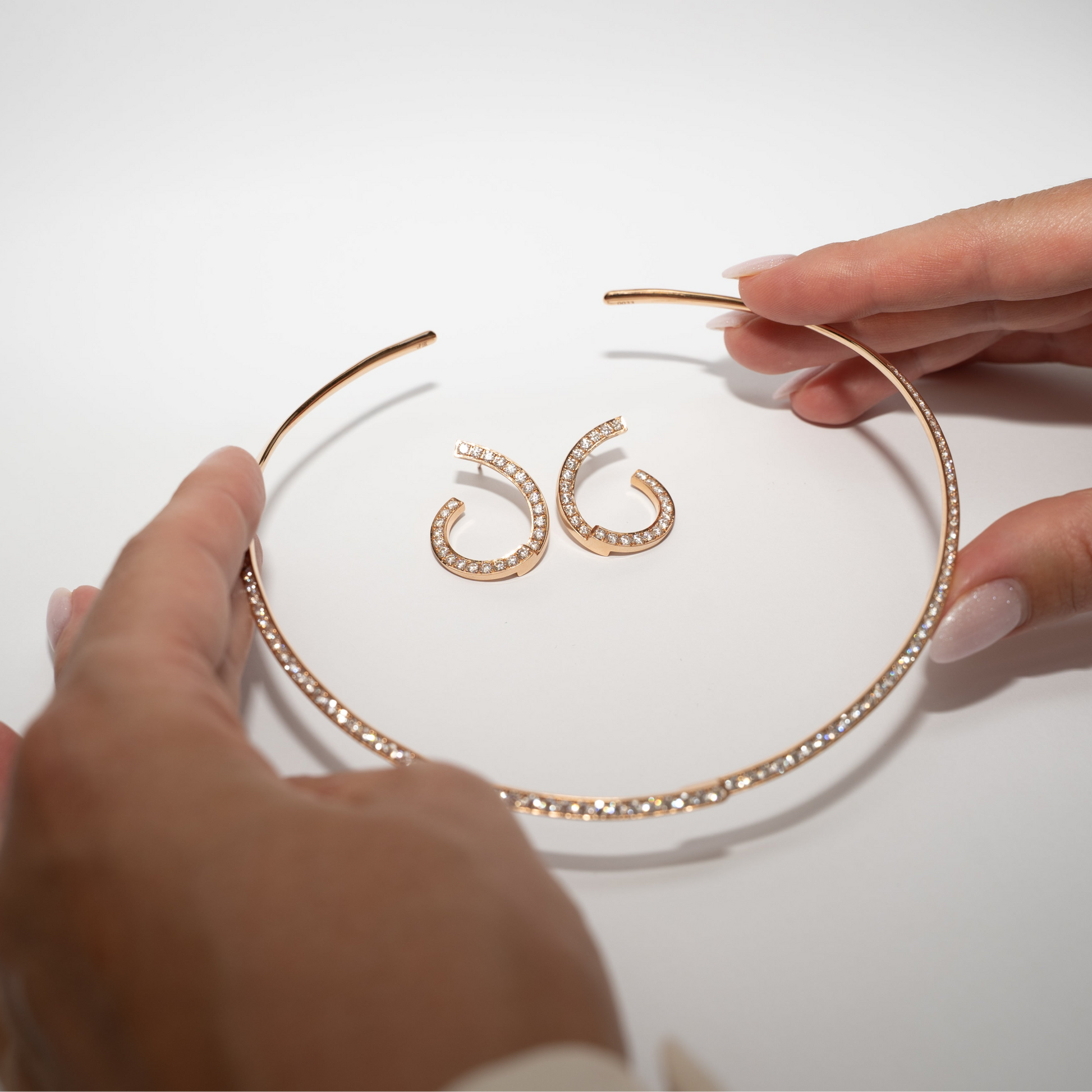Rose Gold necklace and earrings with diamonds on a white box against a gray background