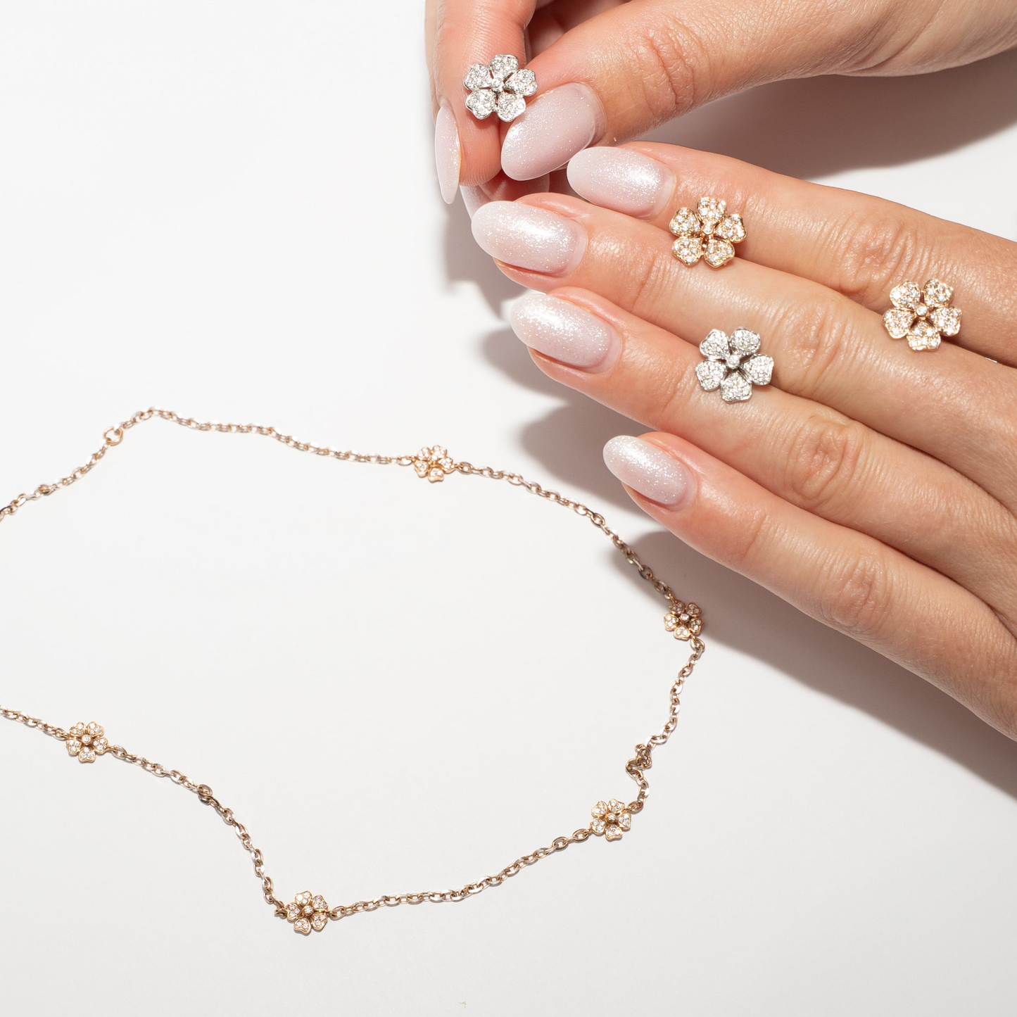 Hand holding a delicate flower earrings diamond and Flower Necklace Diamond Mini out of rose gold with diamonds
