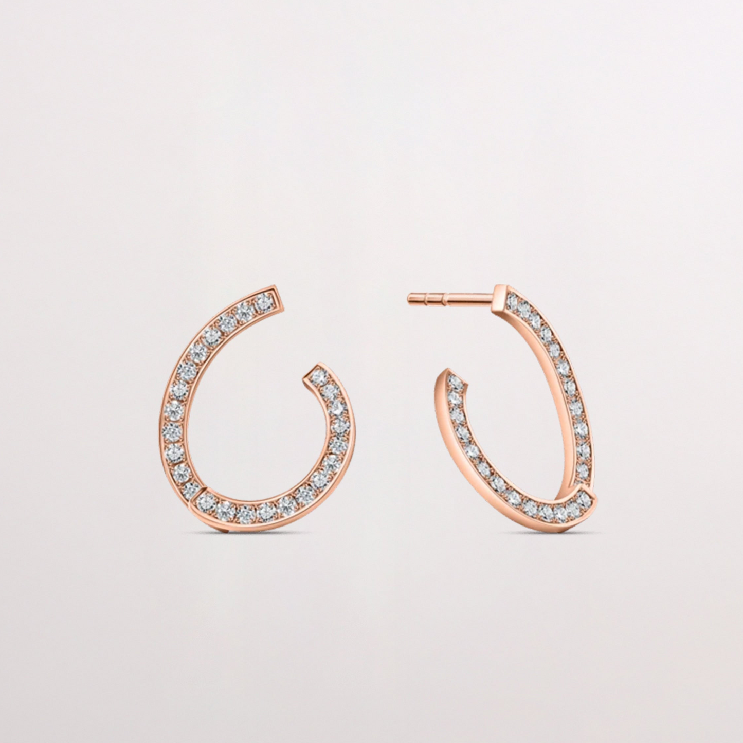 Rose gold hoop earrings with diamonds on a light gray background