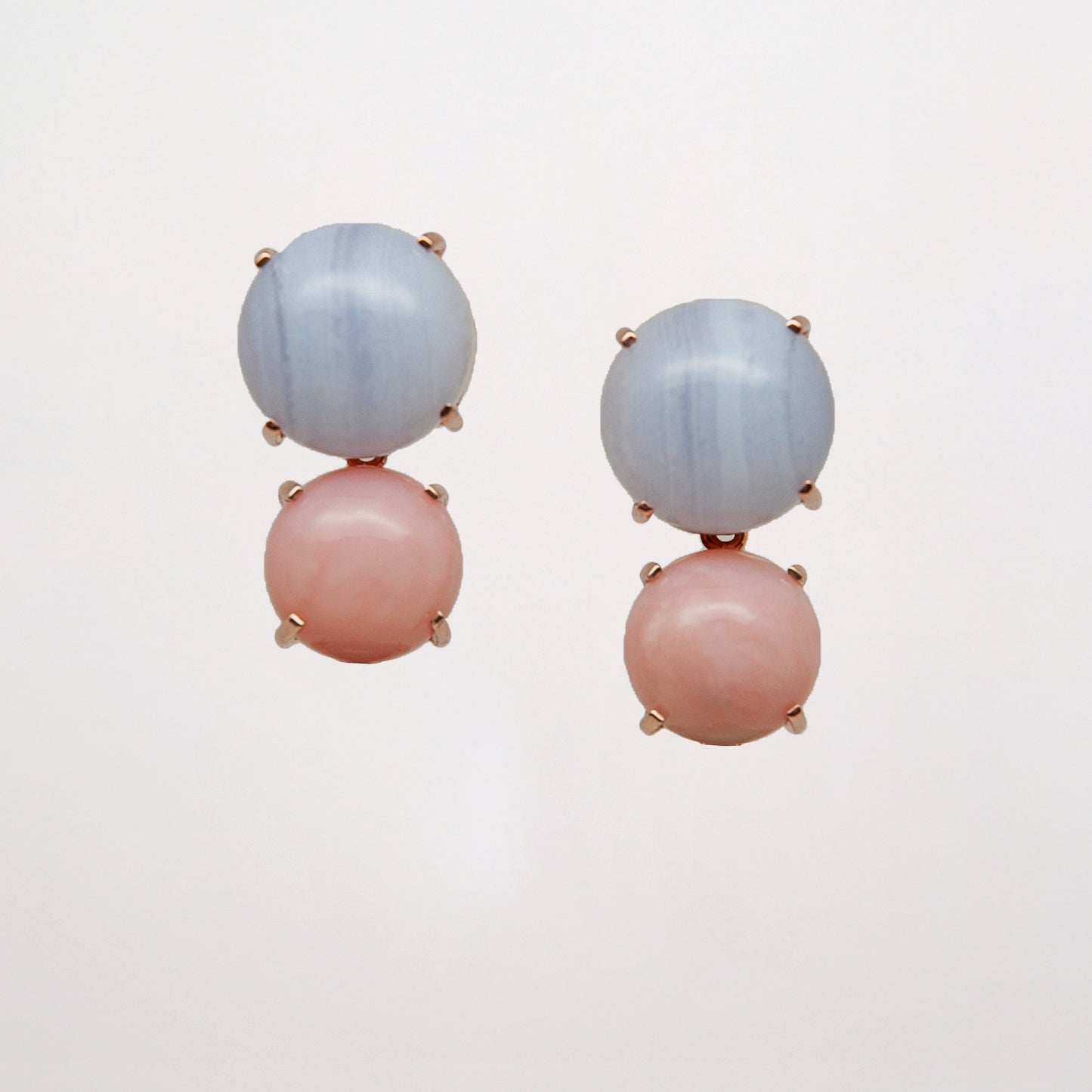 Pair of earrings with pink and blue gemstone on a light gray background