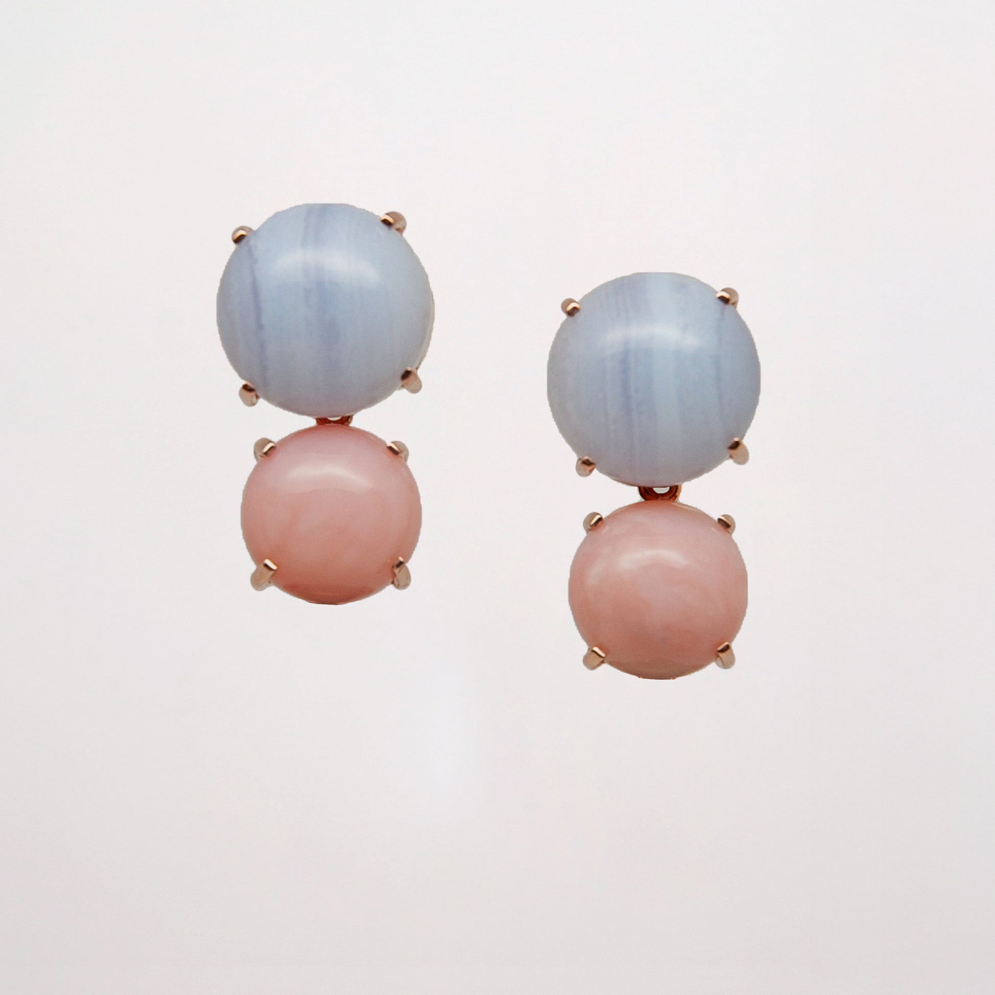 Pair of earrings with pink and blue gemstone on a light gray background