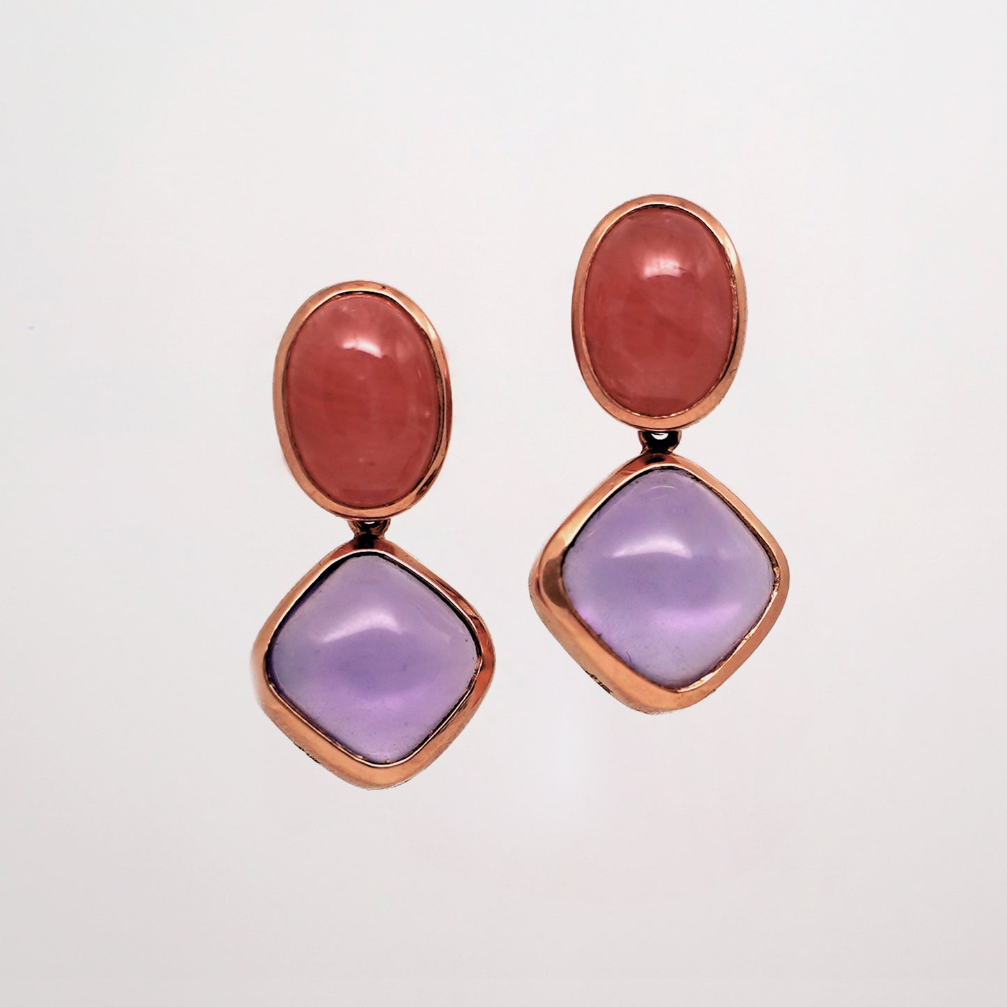 Rhodochrosite and Amethyst Gemstone Stud Earrings. Pair of earrings with pink and purple stones in rose gold on a light gray background